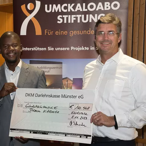 Olaf Schwabe, CEO of the Schwabe Group, presents Mwawi Shaba, the project manager for the St. Steven's School in Malawi, the donation from the Africa Runners."