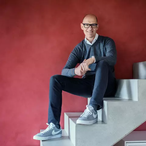 Dr. Traugott Ullrich sitzend auf einer Treppe vor einem roten Hintergund