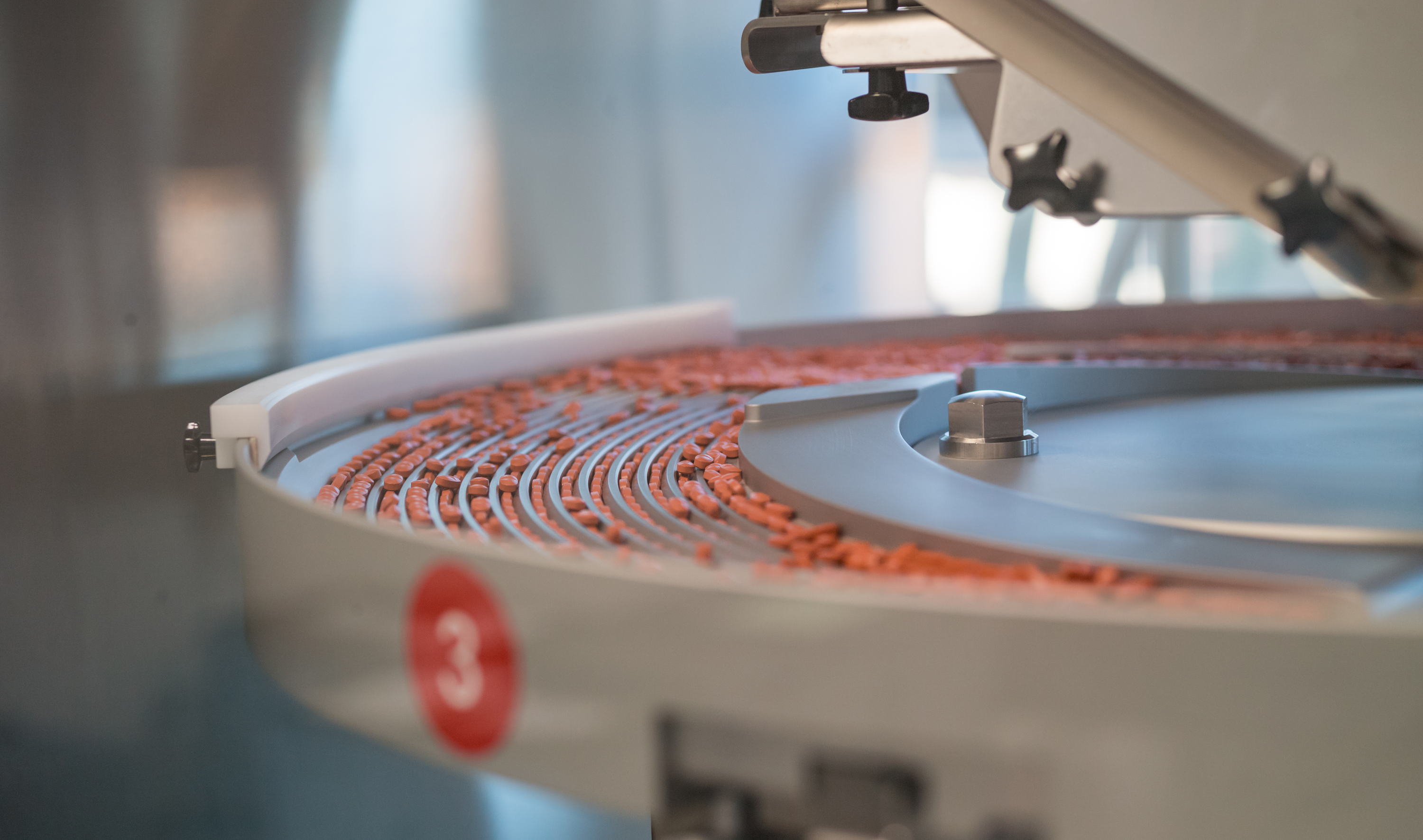Red tablets on a sorter of a packaging line