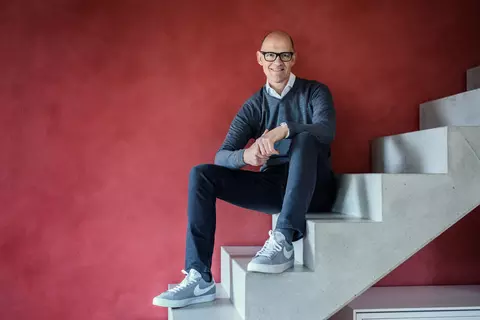 Dr. Traugott Ullrich sitzend auf einer Treppe vor einem roten Hintergund